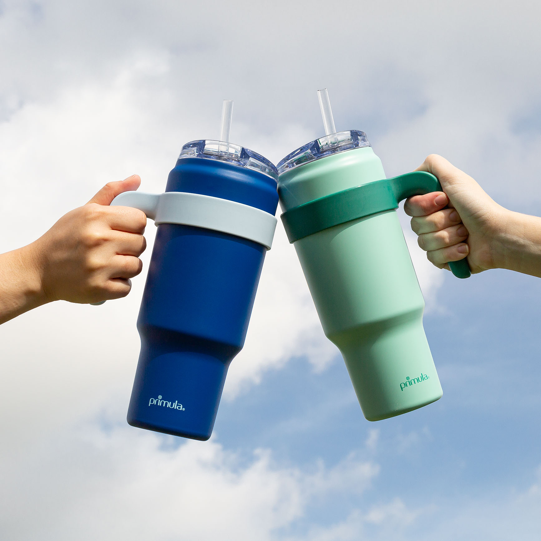 Two people toasting with Primula insulated tumblers against an open sky
