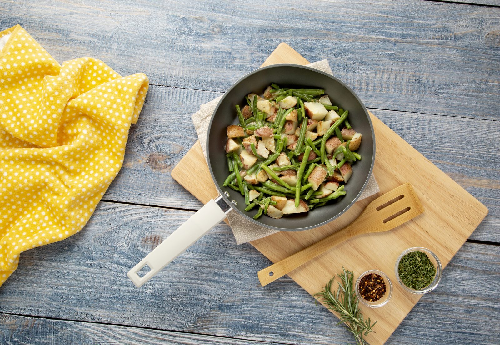 Country Living fry pan of green beans, mushrooms and rice on a yellow linen with parsley and a bamboo board