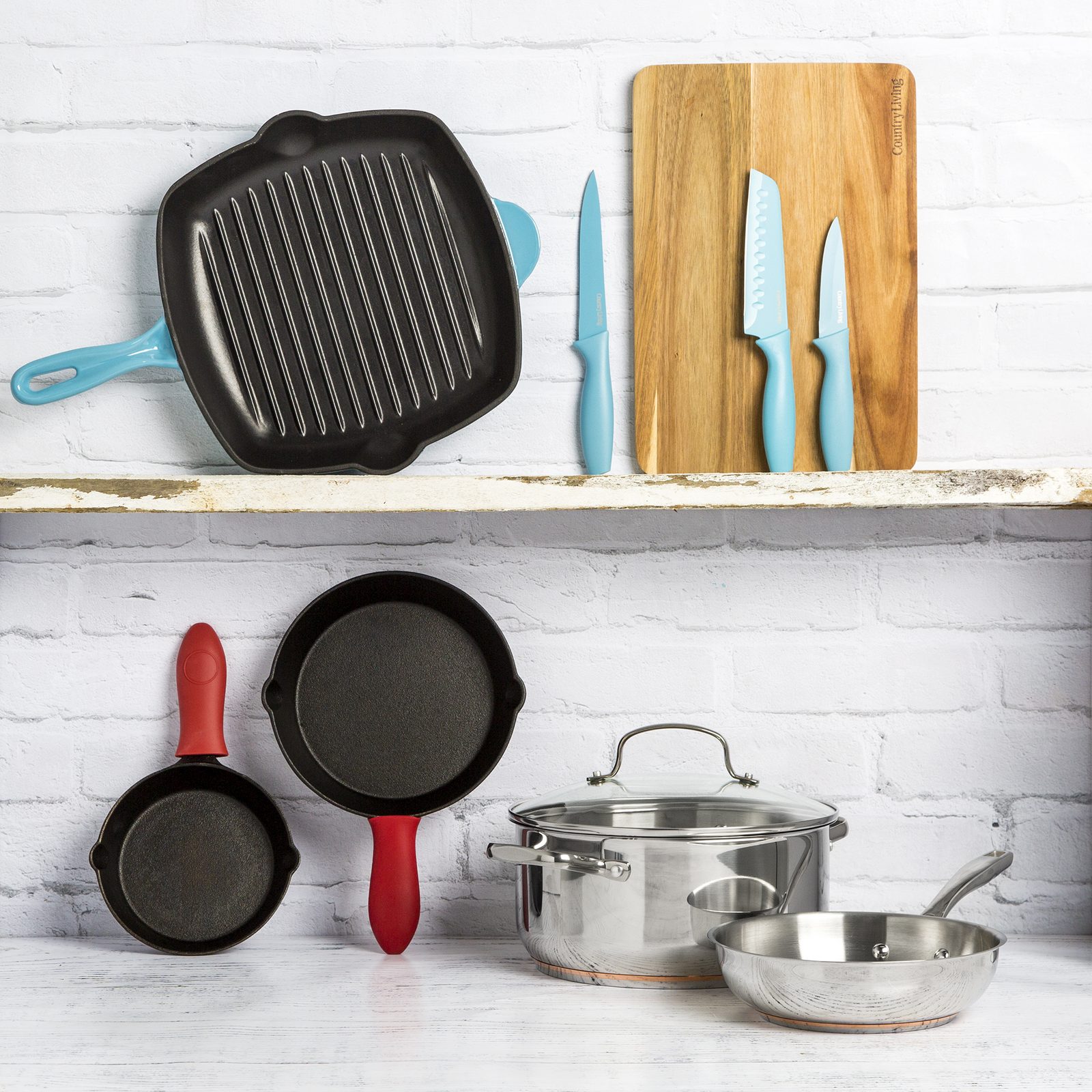Country Living cast iron grill pan, skillets, saucepan, bamboo board and knives styled on a kitchen shelf