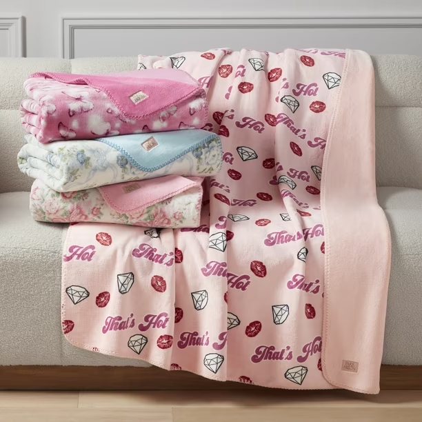 Paris Hilton That's Hot throw blankets, folded and draped on a sofa, an example of the name licensed into home textiles